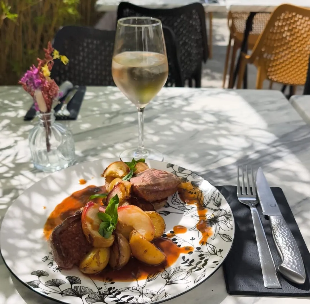 Un plat de viande et pommes de terre grenailles servi en terrasse.