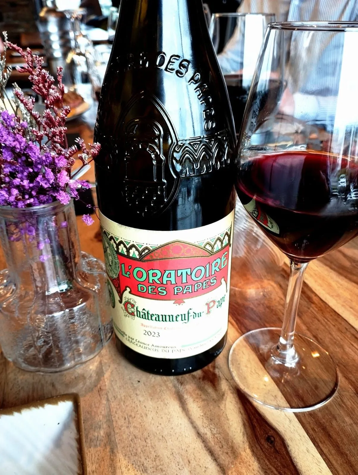 Une bouteille de Châteauneuf-du-Pape et un verre de vin rouge sur une table en bois.